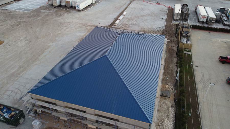 Aerial view of a blue standing seam hip roof on a commercial building