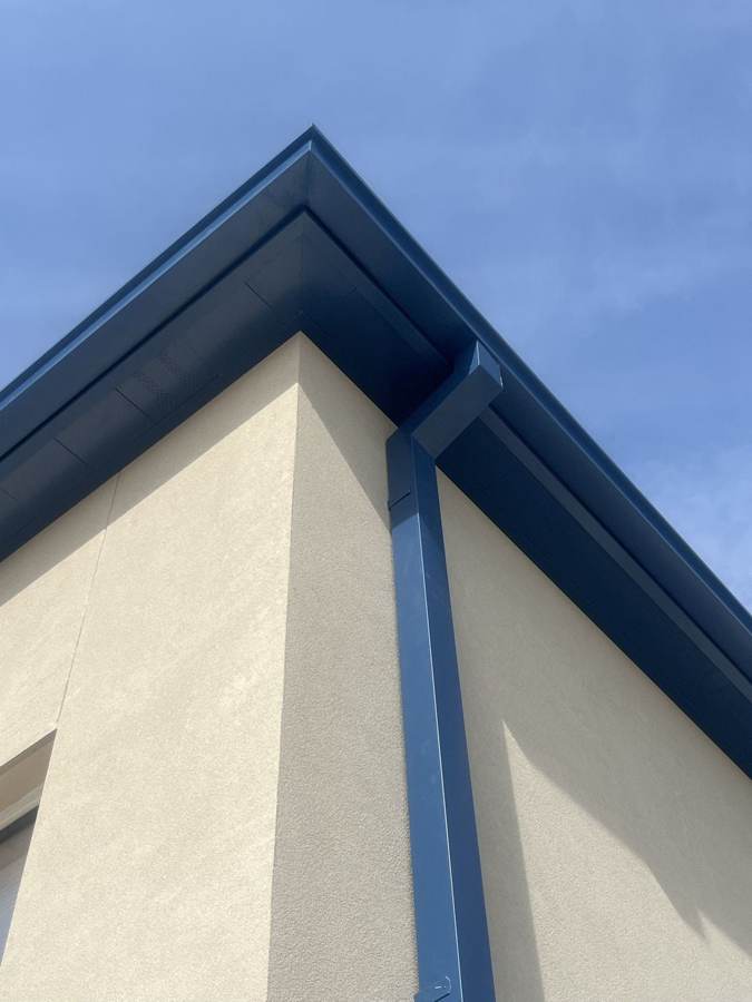 Close view of a blue seamless gutter corner and downspout