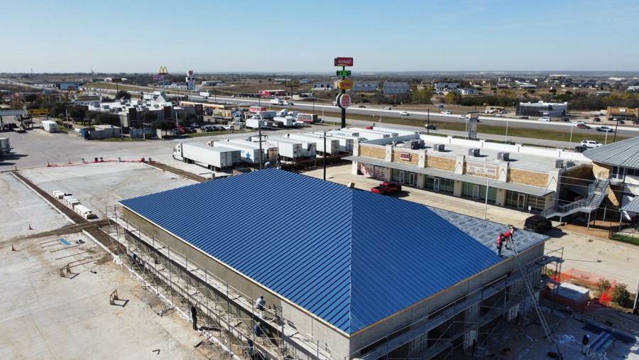 Crew finishing a blue metal roof on a commercial building