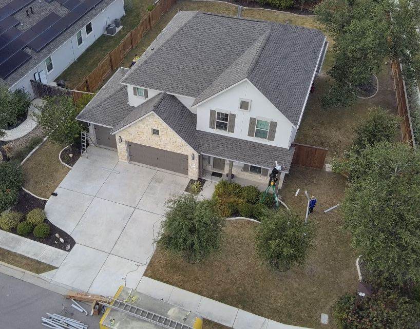 Crew finishing a new shingle roof on a two-story home